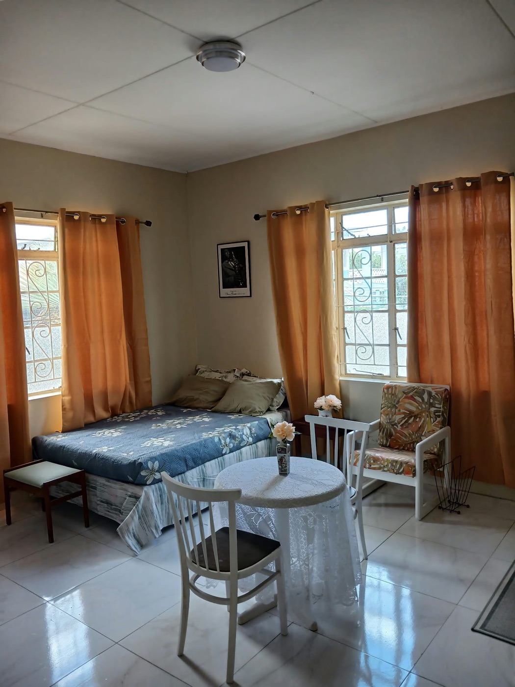 Double bed dressed in blue floral linens between two curtained windows