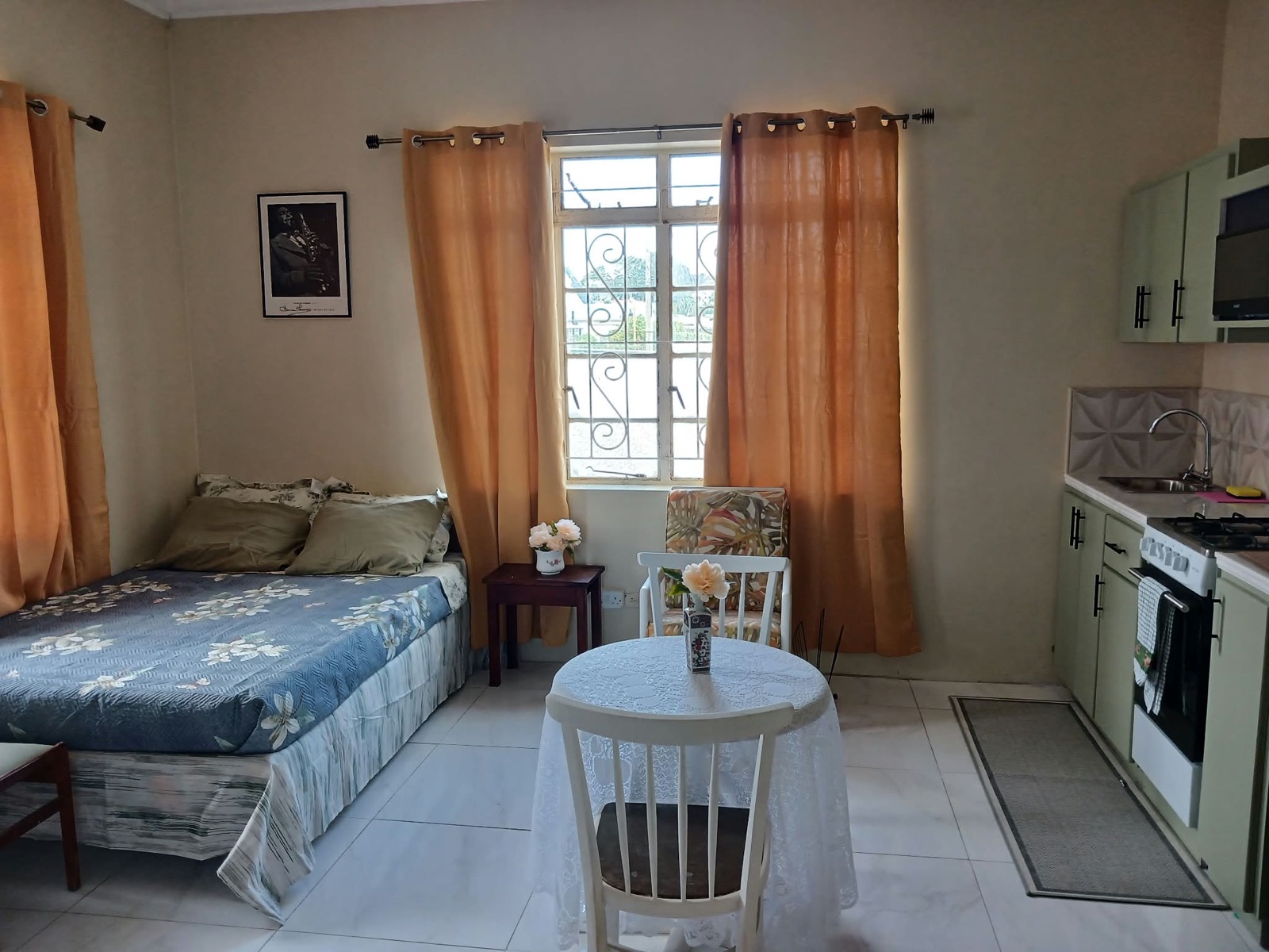 Apartment 1 — open-plan room with double bed, dining table and sage-green kitchenette