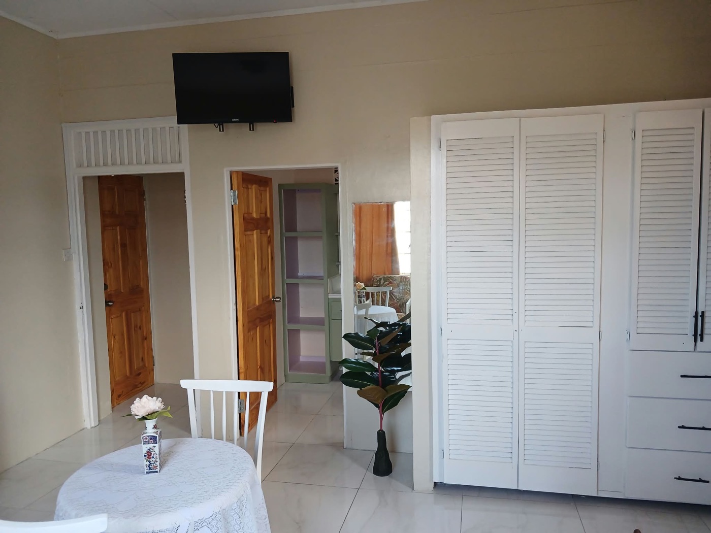 Wall-mounted TV over the louvered wardrobes and hallway