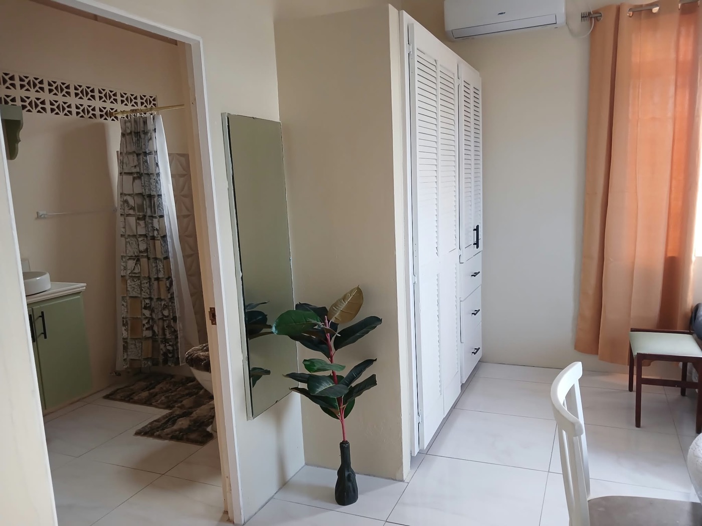 Full wall of white louvered wardrobes with the air conditioner above