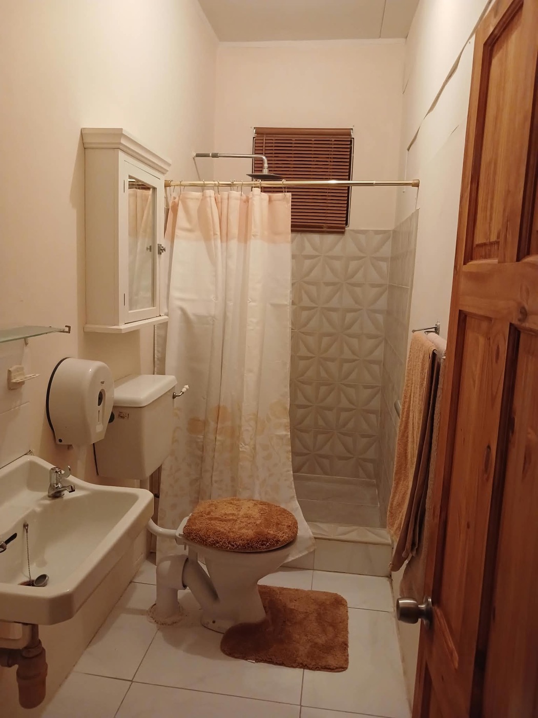 Bathroom with walk-in sculpted-tile shower and wooden blinds