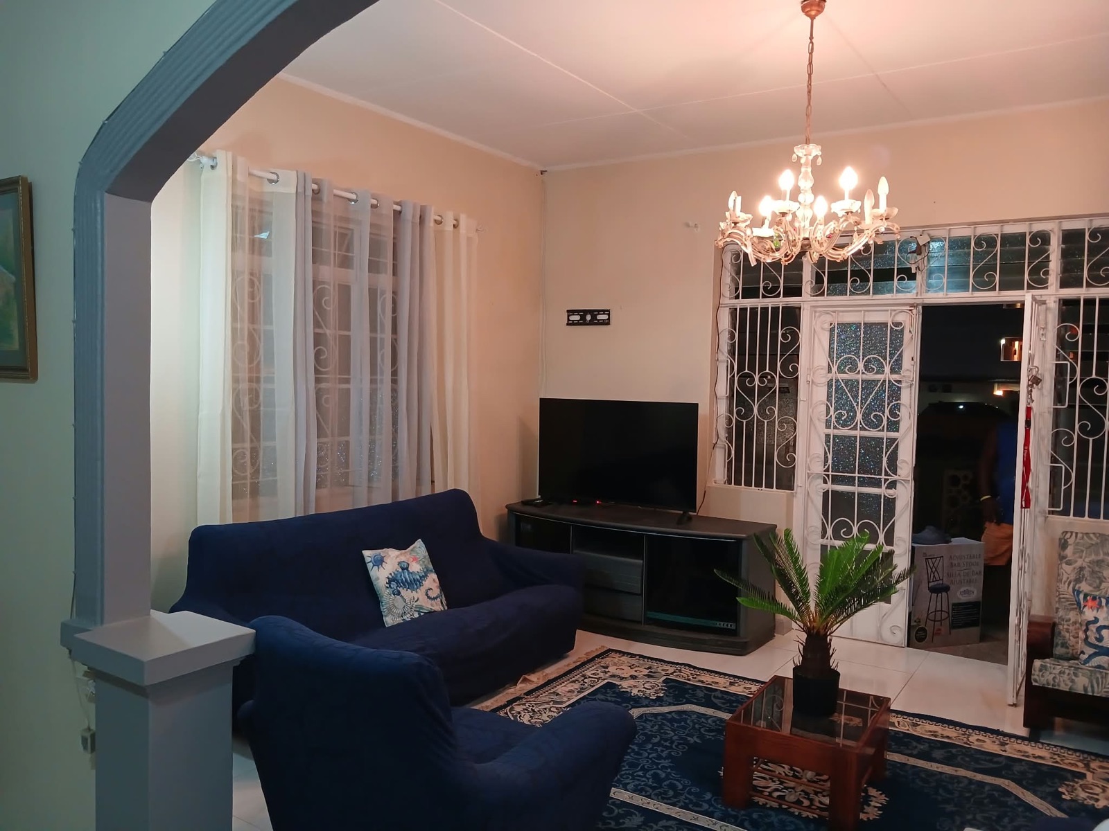 Apartment 2B — living room with navy sofas, chandelier and white wrought-iron doors
