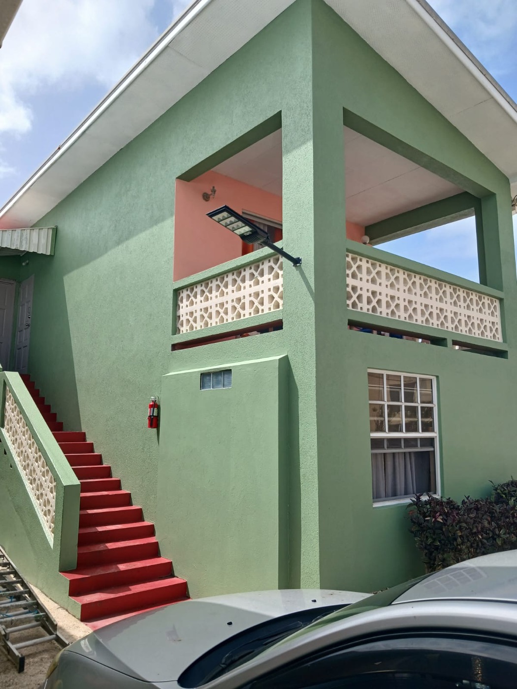 The red staircase up the sage-green annexe
